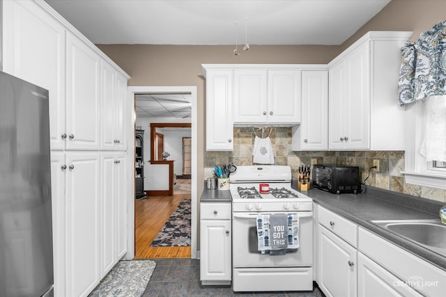 kitchen featuring black fridge, dark wood-type flooring, white cabinets, sink, and white range with gas stovetop