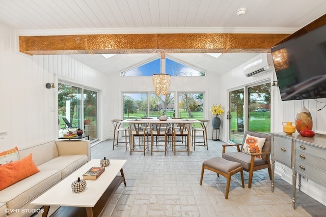 sunroom / solarium with vaulted ceiling with skylight, plenty of natural light, a wall unit AC, and an inviting chandelier