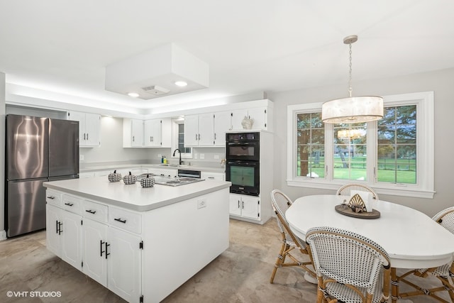 kitchen with pendant lighting, a center island, white cabinets, black double oven, and stainless steel fridge