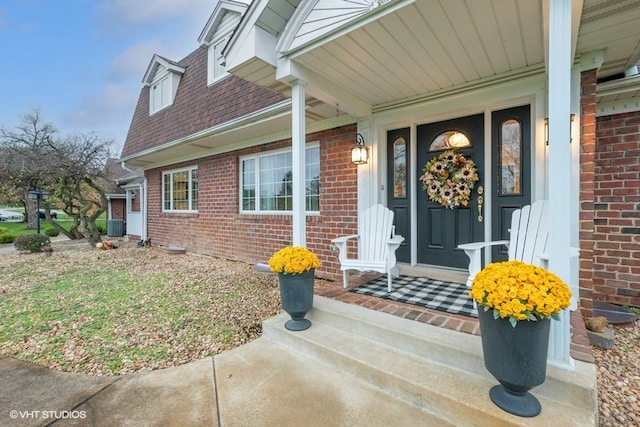 view of exterior entry featuring a porch and central AC