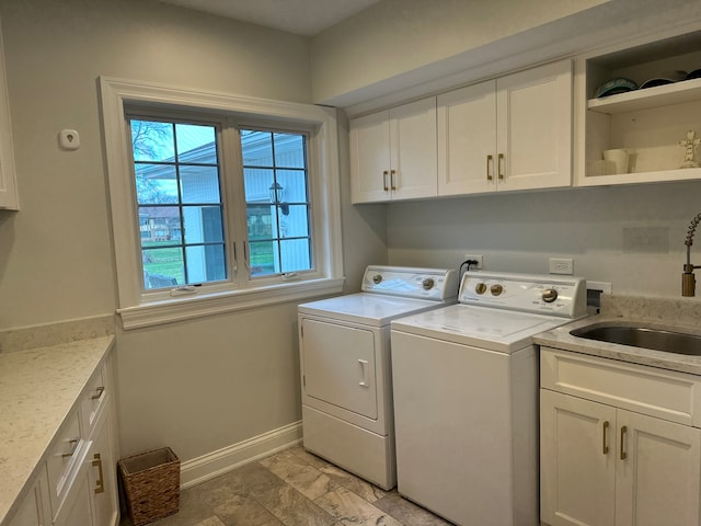 laundry area featuring washer and clothes dryer, cabinets, and sink