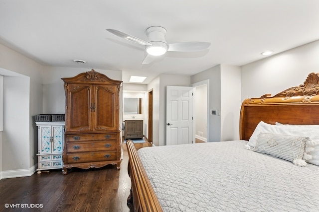 bedroom with dark hardwood / wood-style flooring, a skylight, ensuite bath, and ceiling fan