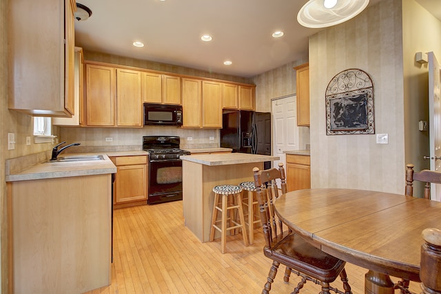 kitchen with light hardwood / wood-style floors, sink, black appliances, light brown cabinetry, and a kitchen island