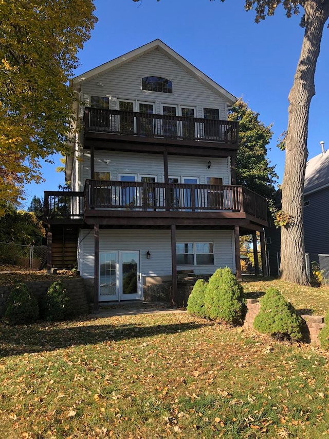 rear view of house featuring a lawn and a deck