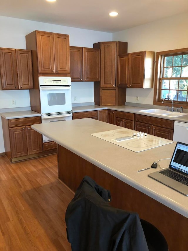 kitchen featuring light wood-type flooring, white appliances, and sink