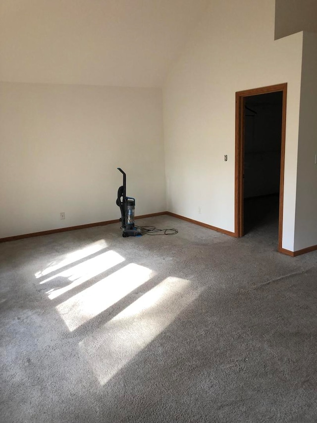 carpeted spare room featuring vaulted ceiling