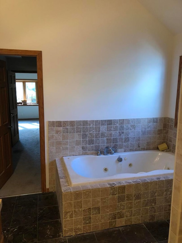 bathroom featuring a relaxing tiled tub and lofted ceiling