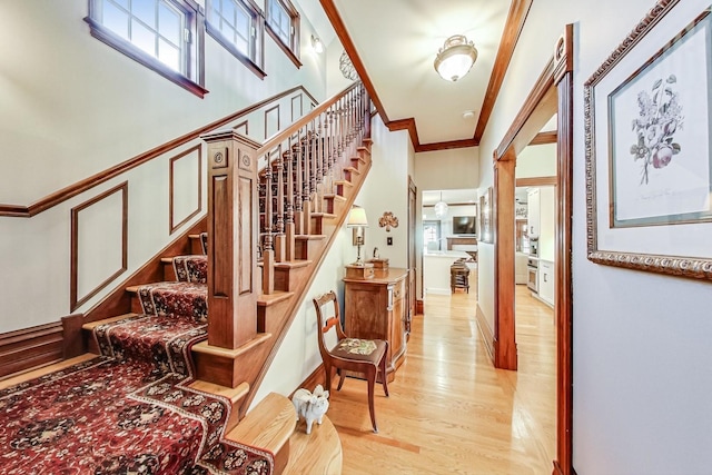 stairs with hardwood / wood-style flooring, plenty of natural light, and ornamental molding