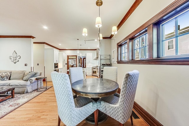 dining area with a notable chandelier, light wood-type flooring, and crown molding