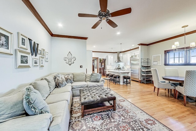 living room with ceiling fan with notable chandelier, light wood-type flooring, and crown molding