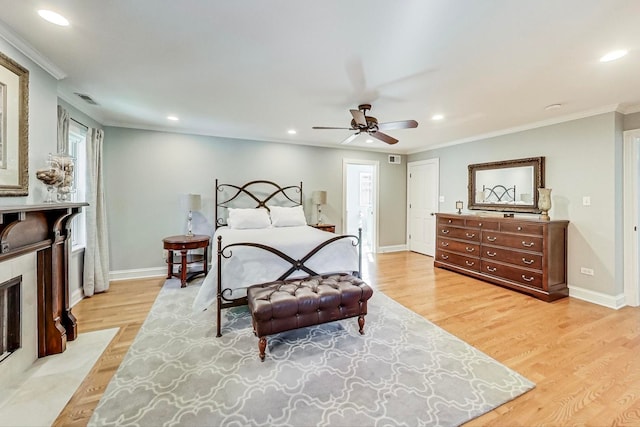 bedroom with ceiling fan, a fireplace, ornamental molding, and light wood-type flooring