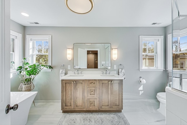 bathroom with a washtub, vanity, and toilet