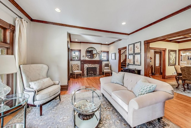 living room featuring hardwood / wood-style flooring, crown molding, and a tiled fireplace