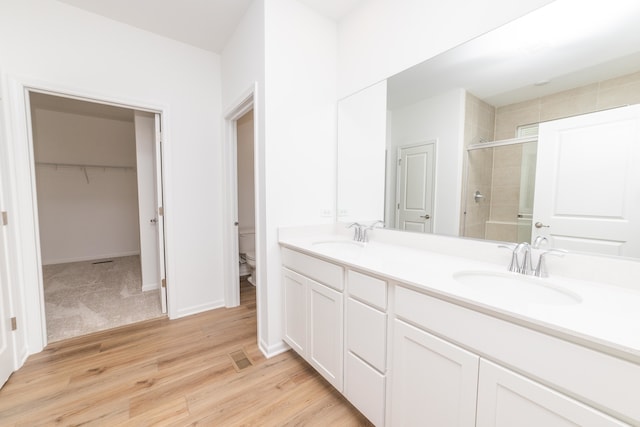 bathroom with toilet, vanity, an enclosed shower, and wood-type flooring