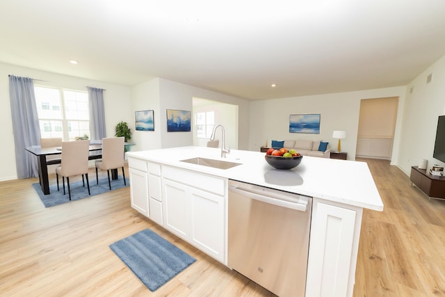 kitchen with white cabinets, sink, an island with sink, stainless steel dishwasher, and light wood-type flooring