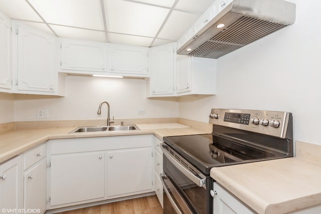 kitchen with electric range, white cabinetry, sink, and extractor fan