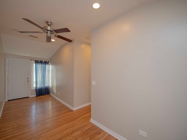 empty room with ceiling fan, light hardwood / wood-style flooring, and vaulted ceiling