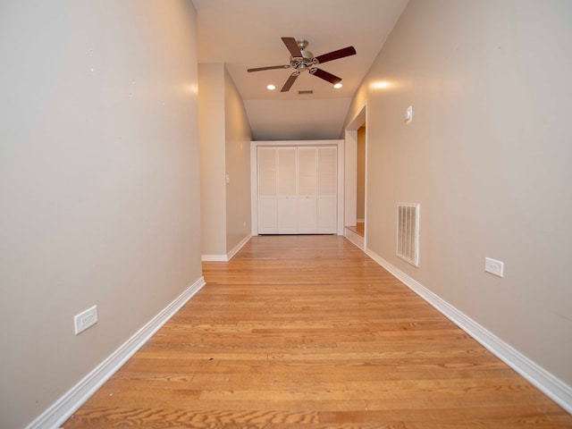 corridor featuring light wood-type flooring and lofted ceiling