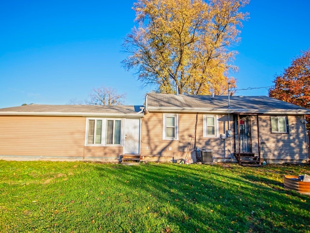 rear view of house featuring central AC and a yard