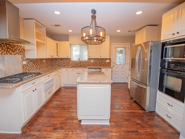 kitchen featuring stainless steel appliances, a kitchen island, wall chimney range hood, decorative light fixtures, and dark wood-type flooring