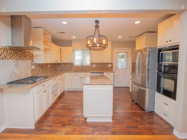 kitchen featuring stainless steel appliances, wall chimney range hood, hanging light fixtures, dark wood-type flooring, and a center island