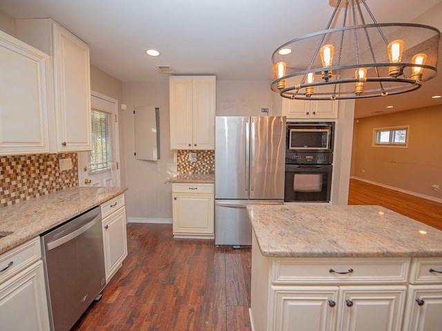 kitchen with stainless steel appliances, dark hardwood / wood-style flooring, light stone counters, white cabinets, and hanging light fixtures