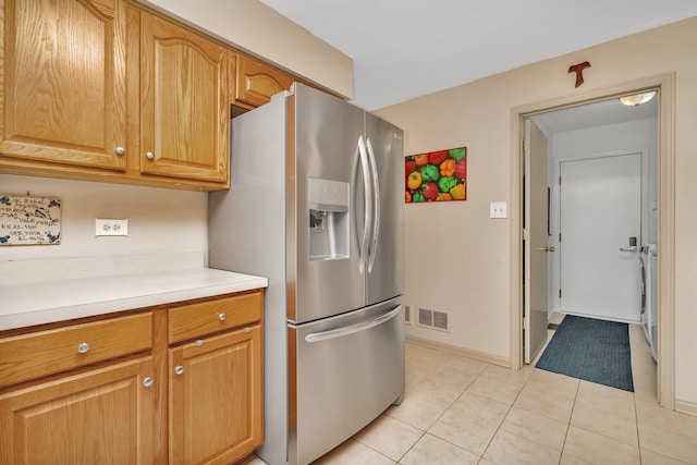 kitchen with light tile patterned floors, stainless steel refrigerator with ice dispenser, and washer / dryer