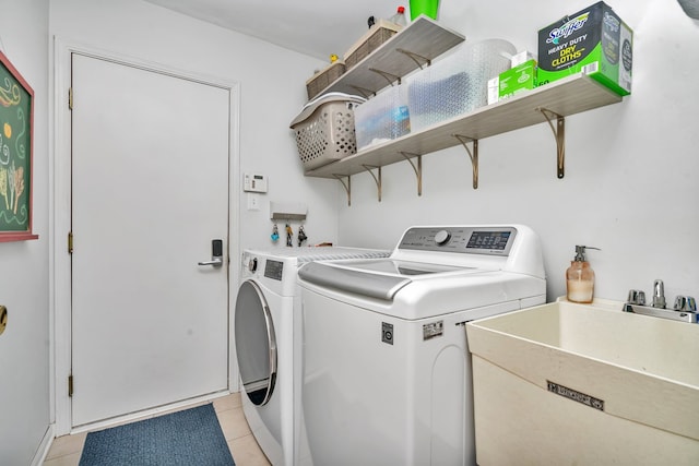 laundry area featuring washing machine and dryer, sink, and light tile patterned flooring