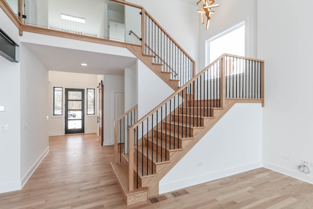 stairs featuring a towering ceiling and hardwood / wood-style floors