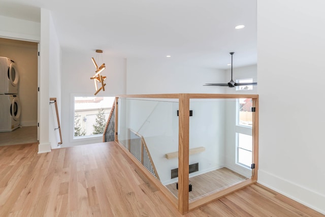 hallway with stacked washer and clothes dryer, a notable chandelier, and light hardwood / wood-style flooring