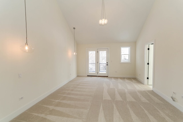 carpeted spare room with high vaulted ceiling and french doors