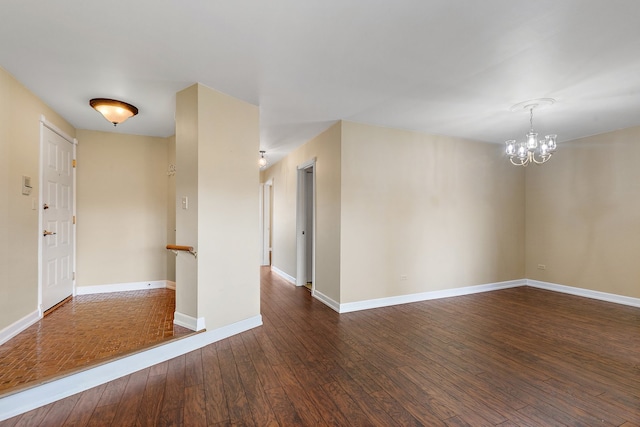 spare room with dark wood-type flooring and an inviting chandelier