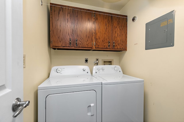 laundry room with electric panel, washer and dryer, and cabinets