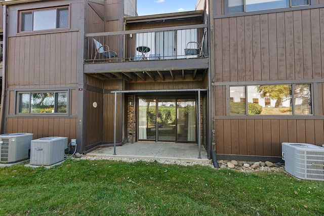 rear view of property featuring a balcony, central AC unit, and a yard