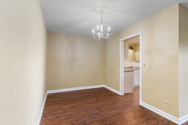 empty room with dark wood-type flooring, a chandelier, and sink