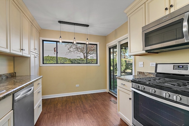 kitchen featuring decorative light fixtures, appliances with stainless steel finishes, cream cabinets, and dark hardwood / wood-style floors