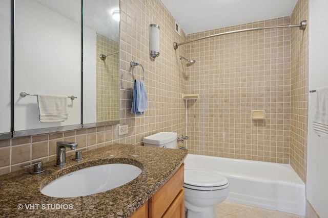 full bathroom with decorative backsplash, tile patterned floors, vanity, tiled shower / bath combo, and tile walls