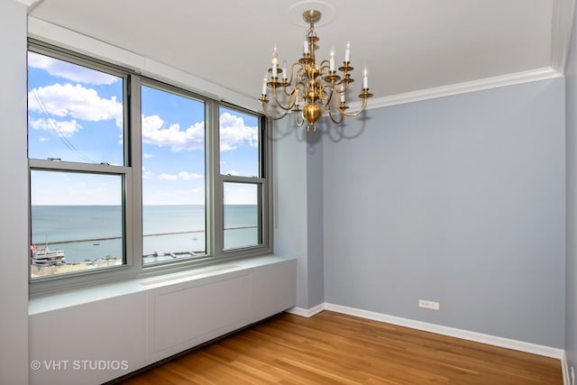 unfurnished room featuring hardwood / wood-style flooring, a notable chandelier, a water view, and ornamental molding