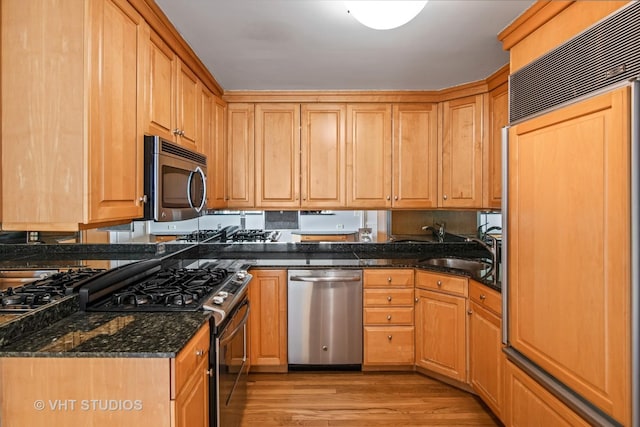 kitchen featuring light wood-type flooring, sink, appliances with stainless steel finishes, and dark stone counters