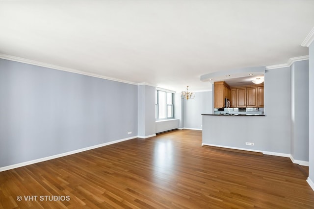 unfurnished living room with hardwood / wood-style floors, an inviting chandelier, and ornamental molding