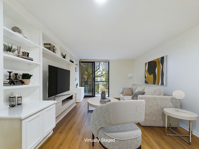 living room featuring hardwood / wood-style flooring, a wall of windows, and built in features