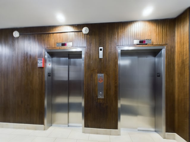 details featuring elevator, wooden walls, and tile patterned flooring