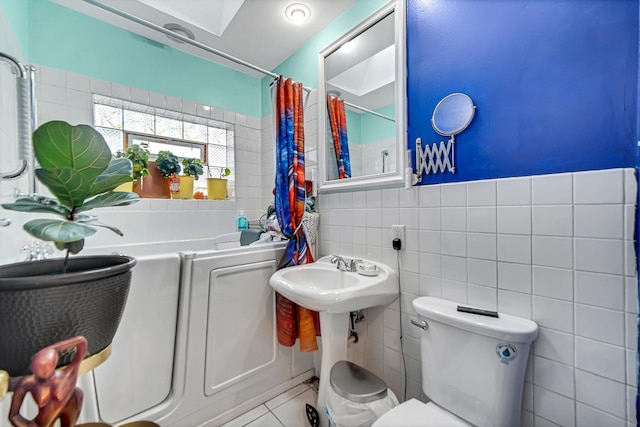 bathroom with tile patterned flooring, toilet, and tile walls