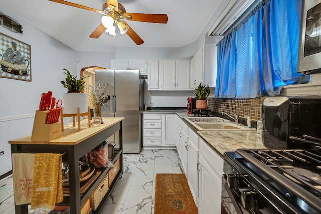 kitchen featuring decorative backsplash, stainless steel fridge, ceiling fan, sink, and white cabinets