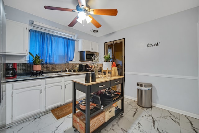 kitchen featuring white cabinets, tasteful backsplash, ceiling fan, and sink