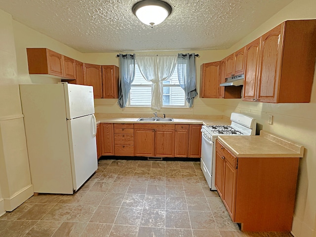 kitchen with a textured ceiling, white appliances, and sink