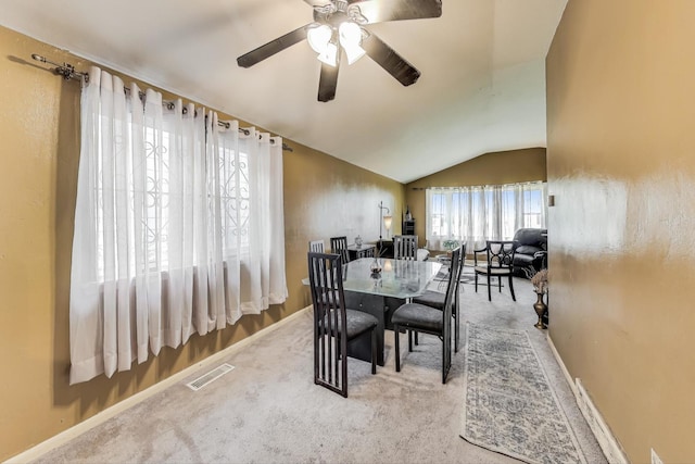 dining space with ceiling fan, light carpet, and vaulted ceiling