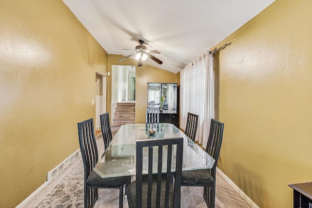 dining space with carpet floors, ceiling fan, and vaulted ceiling