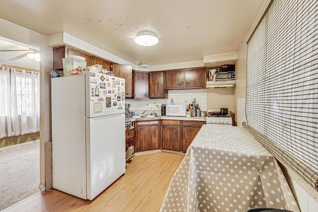 kitchen featuring sink, tasteful backsplash, ceiling fan, light wood-type flooring, and white appliances