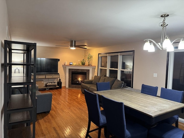 dining area with ceiling fan with notable chandelier and hardwood / wood-style flooring